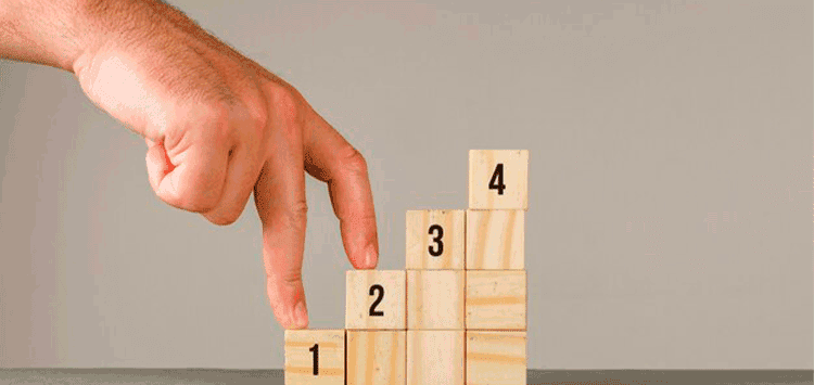 Uma mão colocando um bloco de madeira no topo de um conjunto de números