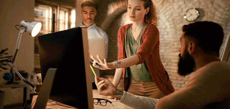 Dois homens e uma mulher olhando para a tela de um computador