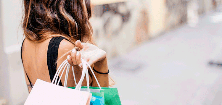 Uma mulher carregando sacolas de compras por uma rua