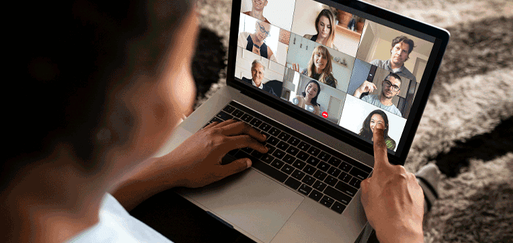 Uma pessoa está usando um laptop com um grupo de pessoas na tela
