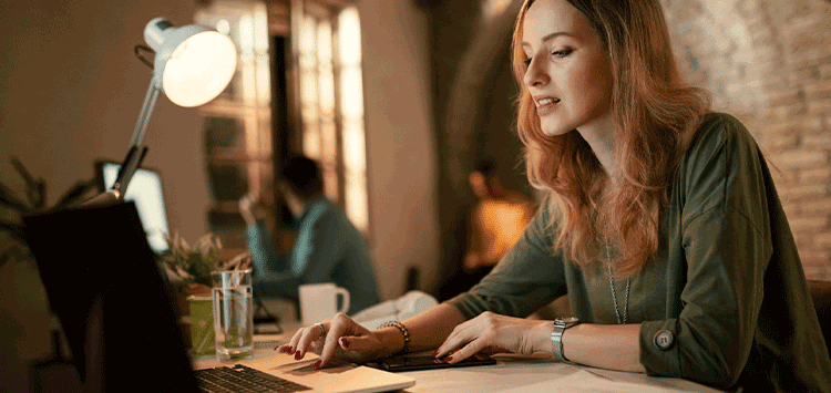 Uma mulher sentada à mesa usando um laptop