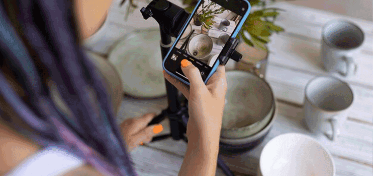 Uma mulher tirando foto de vasos e xícaras com seu celular