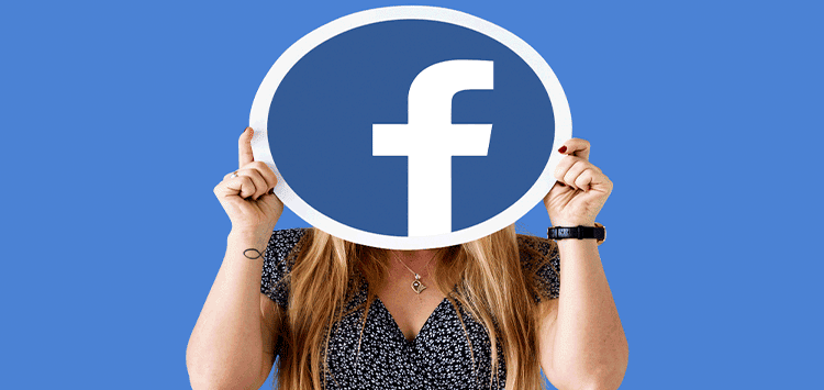 Uma mulher segurando um grande logo do Facebook