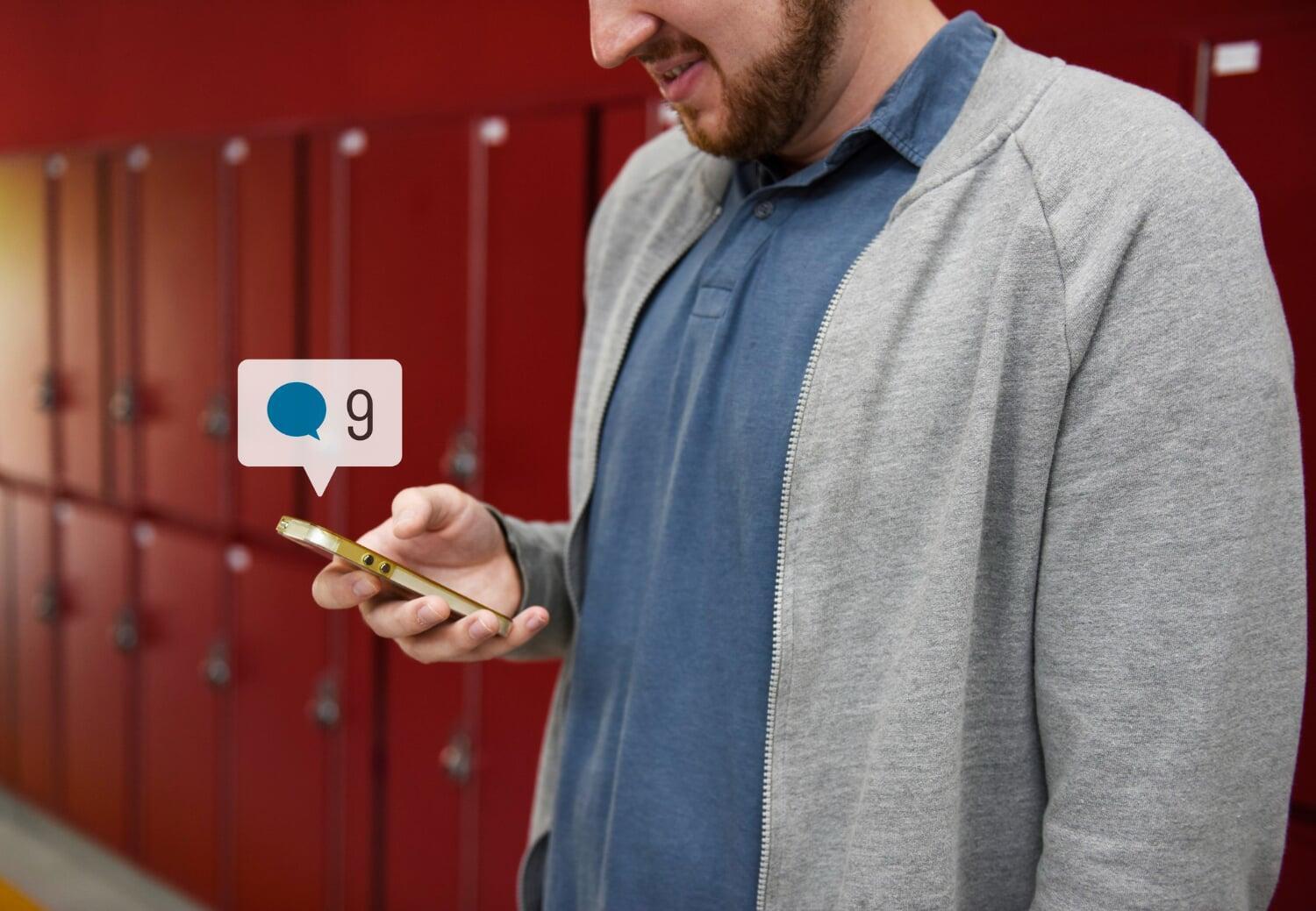 Homem recebendo notificações em seu celular com expressão de satisfação