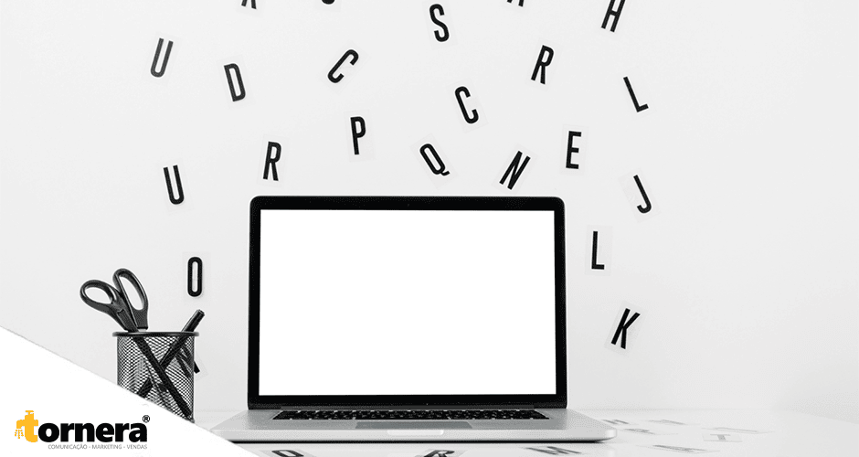 Notebook com tela em branco sobre mesa branca cercada por letras espalhadas