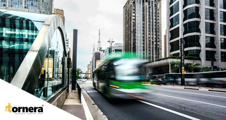 Um ônibus verde e branco passando por uma rua próxima a prédios altos