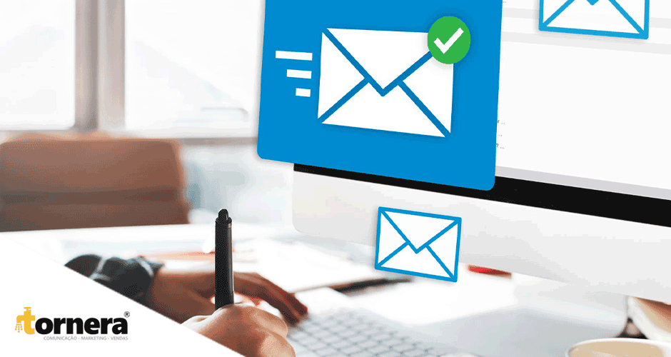 Uma pessoa escrevendo em frente a um computador com um ícone de email na tela